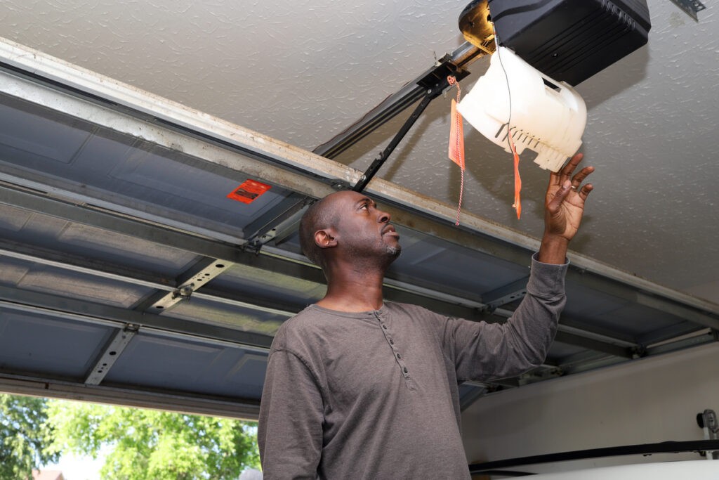 A portrait of a black African-American man changing a lightbulb in a overhead garage