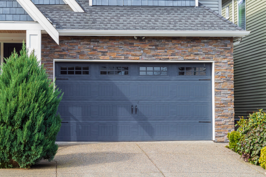 A luxury home with a gray double garage door with windows.